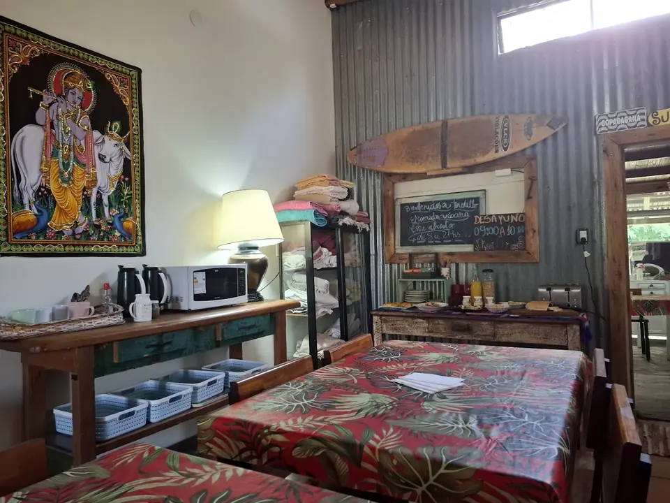 El desayunador con manteles de colores, la cocina compartida y un tapiz en la pared.